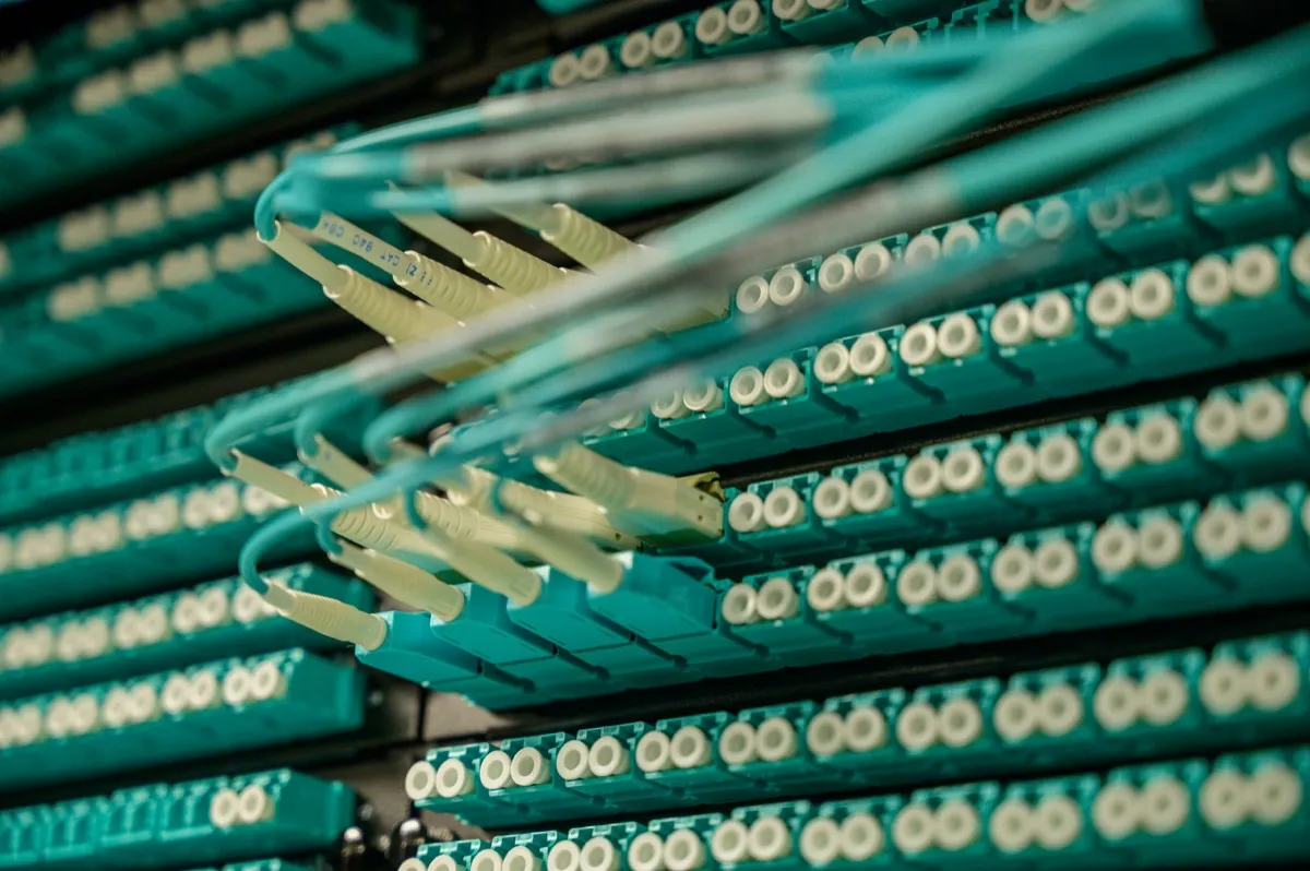 Fiber optic cables plugged into networking equipment in a data center.